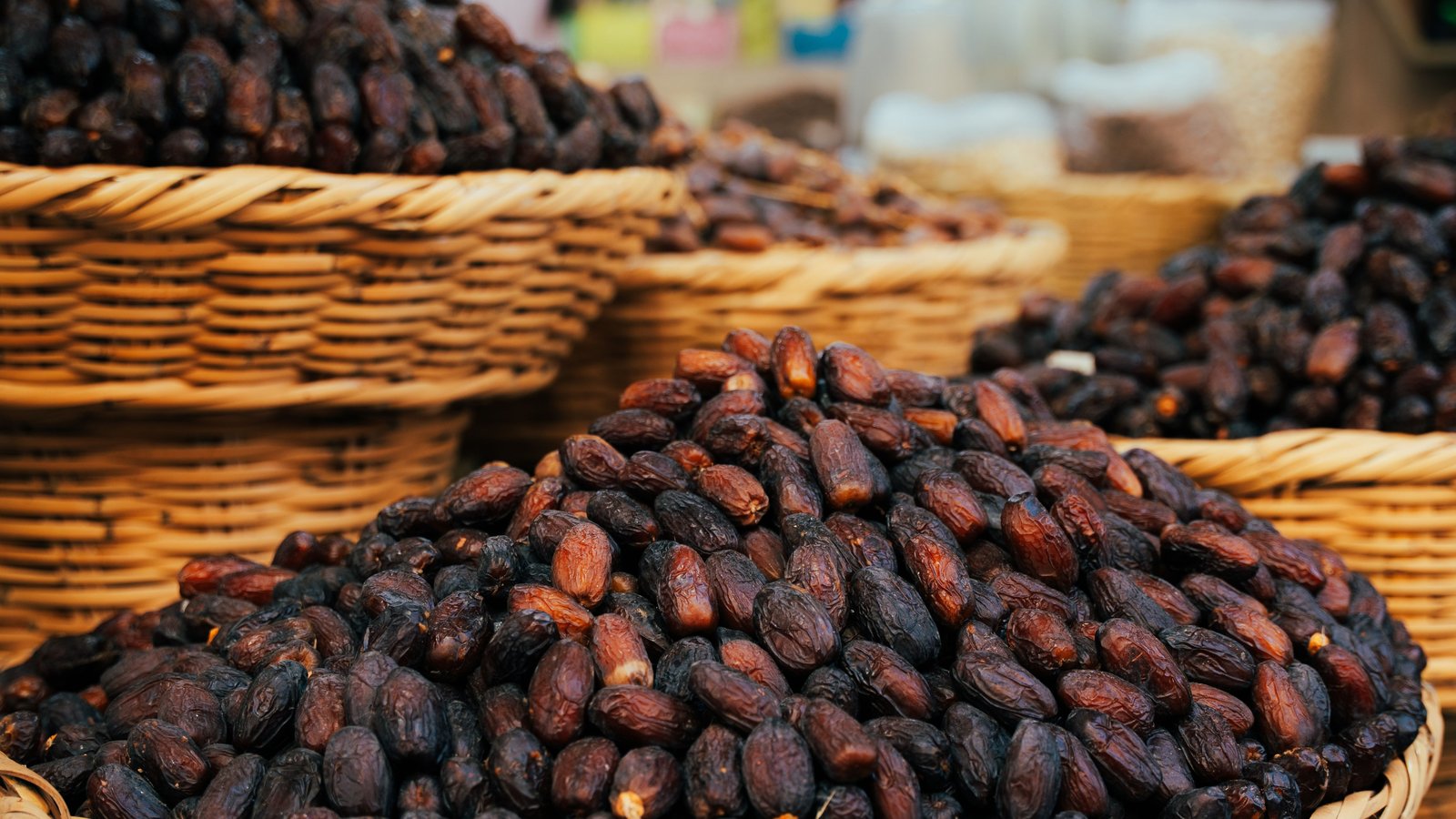 Woven baskets piled high with dates at a market stall, typical of an Arabic grocery