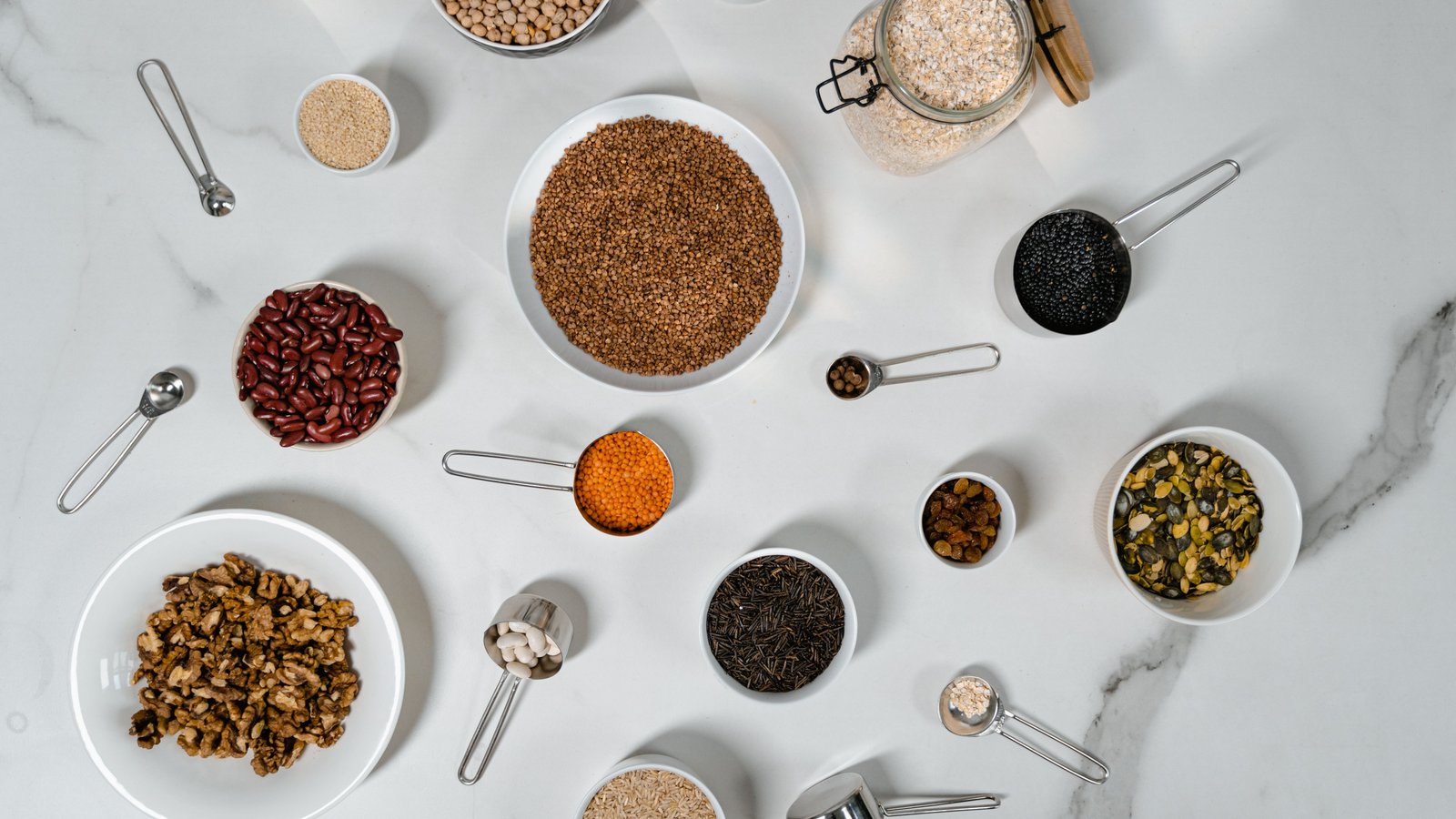 A flat lay of assorted fibre-rich grains, legumes, and seeds in bowls, representing gut-health-supporting foods