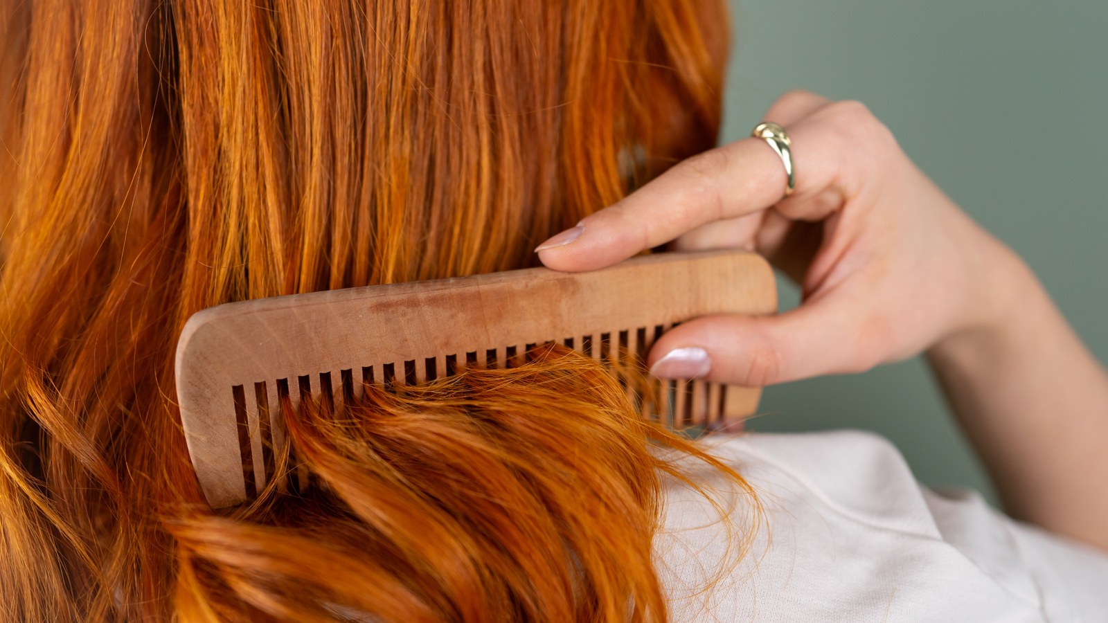 Close-up of a wooden comb running through smooth, shiny hair