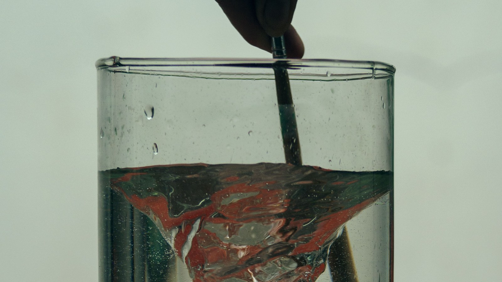 Arabic Gum powder being mixed into a glass of water with a spoon