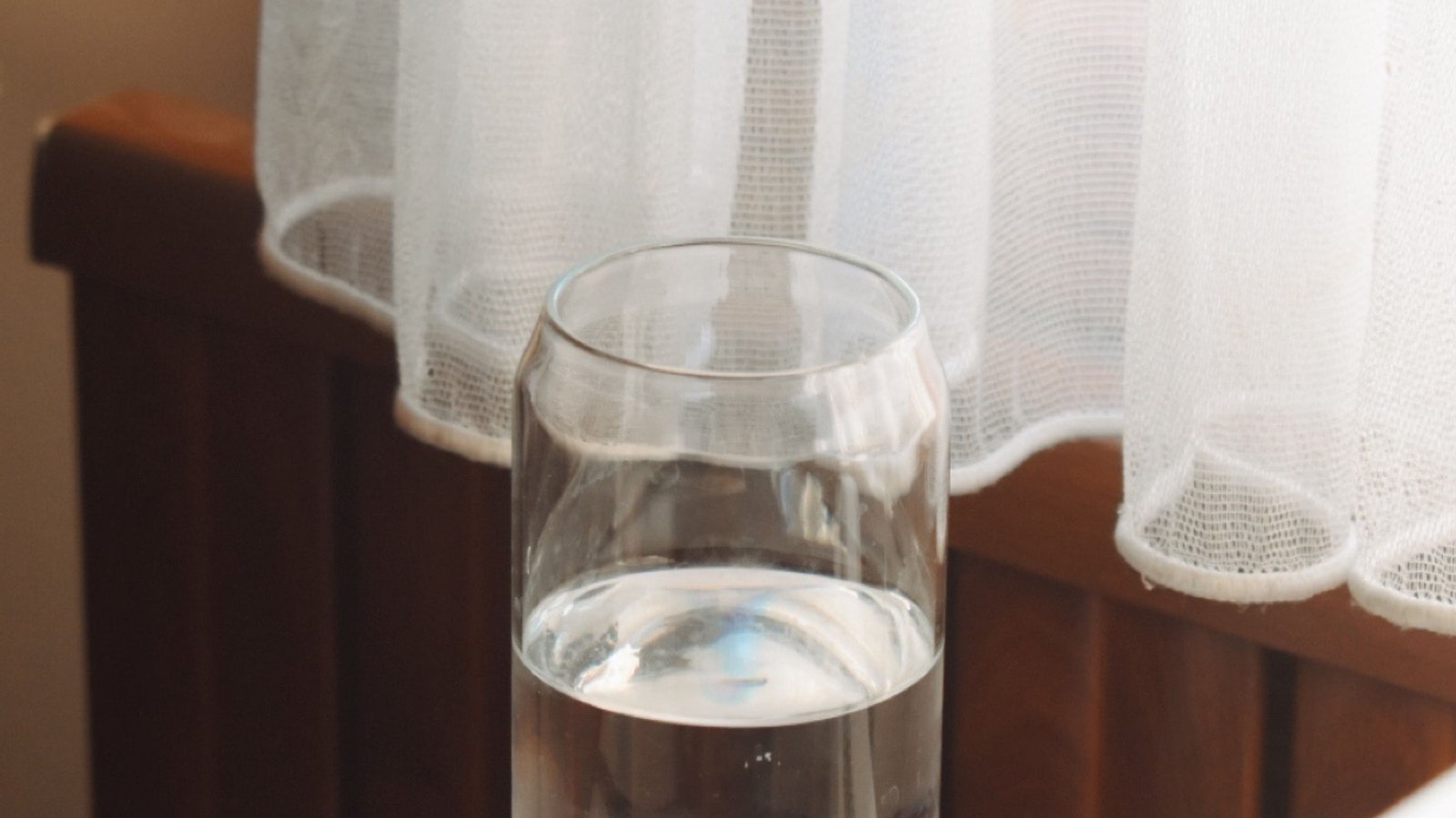 A glass of water in warm morning window light, representing the choice of when to drink Arabic Gum