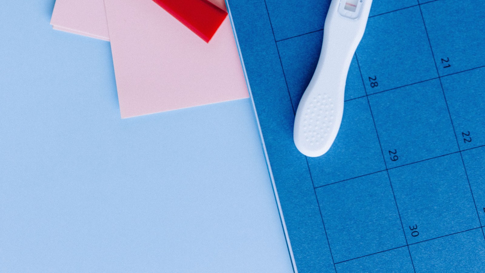 A pregnancy test and calendar flat lay, representing questions about taking Arabic gum during pregnancy