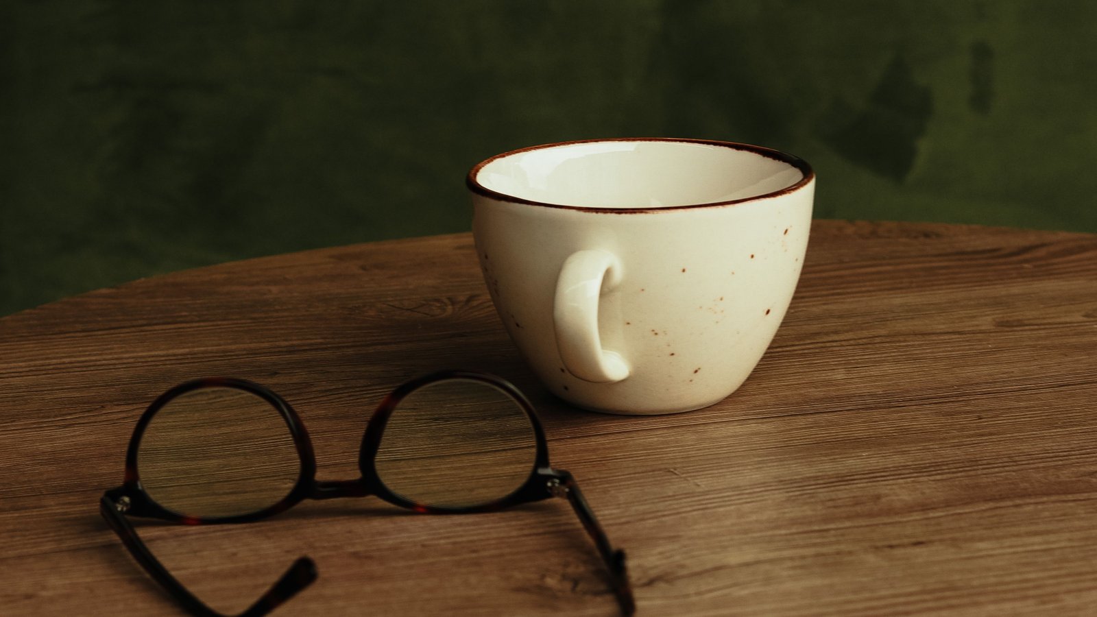 Reading glasses and a ceramic cup on a wooden table, representing a calm daily routine for older adults
