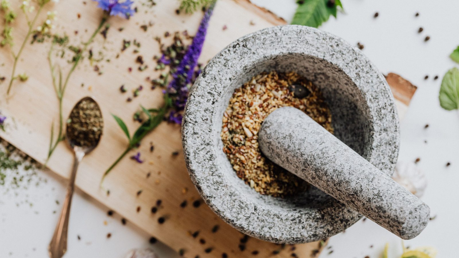 Lesung batu dan alu dengan herba dan botani kering di atas papan kayu, penyediaan perubatan tradisional