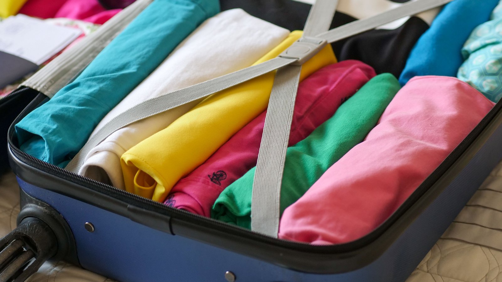 A neatly packed suitcase with rolled colourful clothes, representing preparing a routine for travel